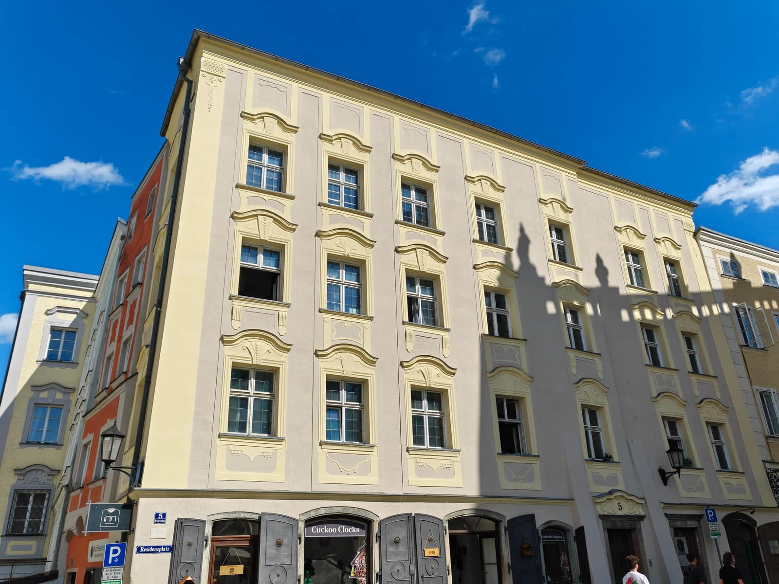 Der barocke Eckbau Residenzplatz 5 in der Passauer Altstadt – die Fassade des InnResidenz-Kuckucksuhrenladens mit dem „Cuckoo Clocks“-Schild und der Hausnummer 5